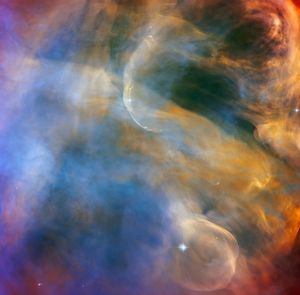 Clouds of blue, orange, yellow, and red fill the scene. wispy-white shockwave arcs stream across the colorful background.
